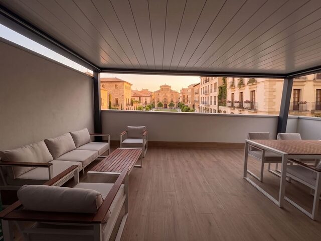 Pérgola bioclimática CERCA en la terraza de un ático, con vistas a la ciudad, a última hora de la tarde